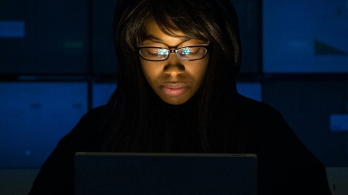 Woman immersed in laptop work during nighttime. Technology and focus in action.