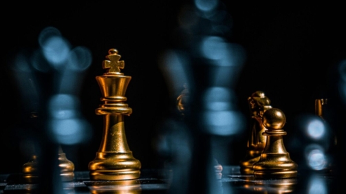 Captivating close-up of gold chess pieces on a board with a dramatic black background.